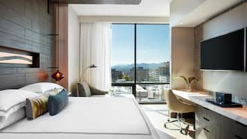 A modern hotel room with a large bed, a desk, and a TV.