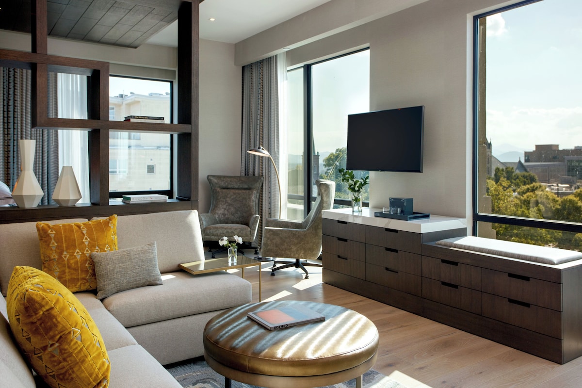 Una sala de estar moderna con un sofá, sillones, una mesa de centro y un televisor montado en la pared.