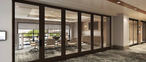 A modern conference room with glass partitions, a marble reception desk, and a view of the cityscape.