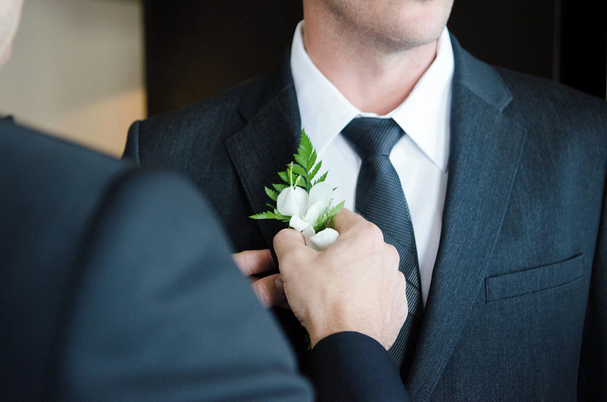 Une personne ajuste une boutonnière sur la veste d’un costume.