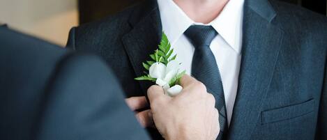 Une personne ajuste une boutonnière sur la veste d’un costume.