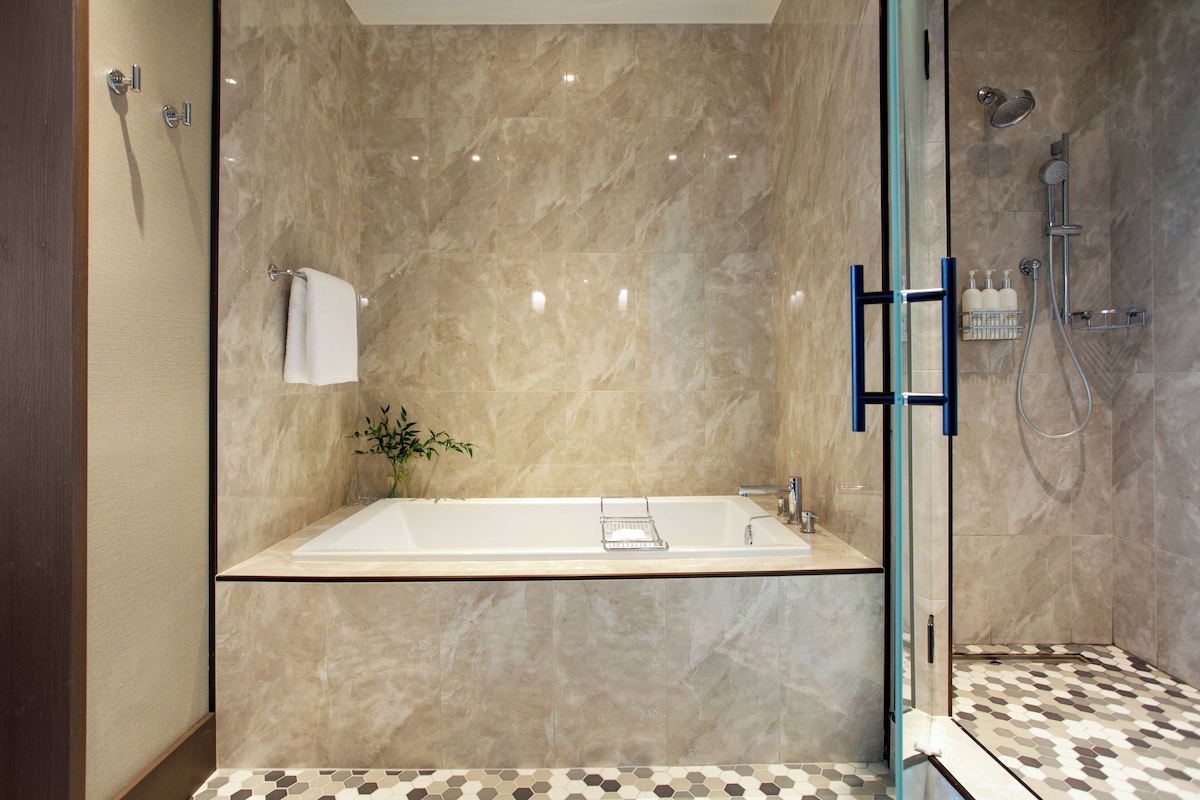 Un baño moderno con una bañera grande, ducha con cerramiento de vidrio y piso estampado.