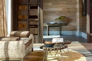 A modern living room with a leather sofa, a coffee table with a bowl, and a bookshelf.