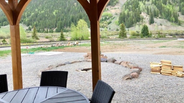 A covered outdoor seating area with a view of a forested hillside.