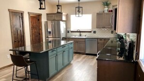 A modern kitchen with a central island, built-in appliances, and pendant lighting.