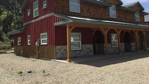 A two-story wooden house with a covered porch and stone foundation.