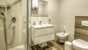 Une salle de bain moderne avec une douche à l’italienne en verre, un meuble-lavabo avec un miroir, un lavabo, un bidet et des toilettes.