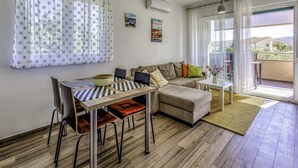 Un salon moderne avec un canapé, une table à manger et des chaises, ainsi qu’un petit balcon.