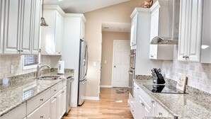 A kitchen with granite countertops, stainless steel appliances, and white cabinetry. - Secluded 3BR private home on golf course! (Edisto Beach)