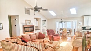 A spacious living area with a sectional sofa, a dining table with chairs, a kitchen area, and a ceiling fan. - Secluded 3BR private home on golf course! (Edisto Beach)