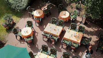 An outdoor patio with tables and chairs, some covered by umbrellas.