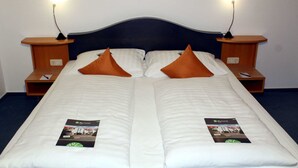 Una cama doble con dos almohadas, mesitas de noche y un folleto a cada lado.