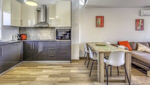Een moderne keuken met een inbouwoven en een eethoek met een houten tafel en stoelen.
