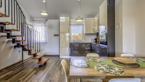 Een moderne keuken met een eethoek, houten vloeren en hangende lampen.
