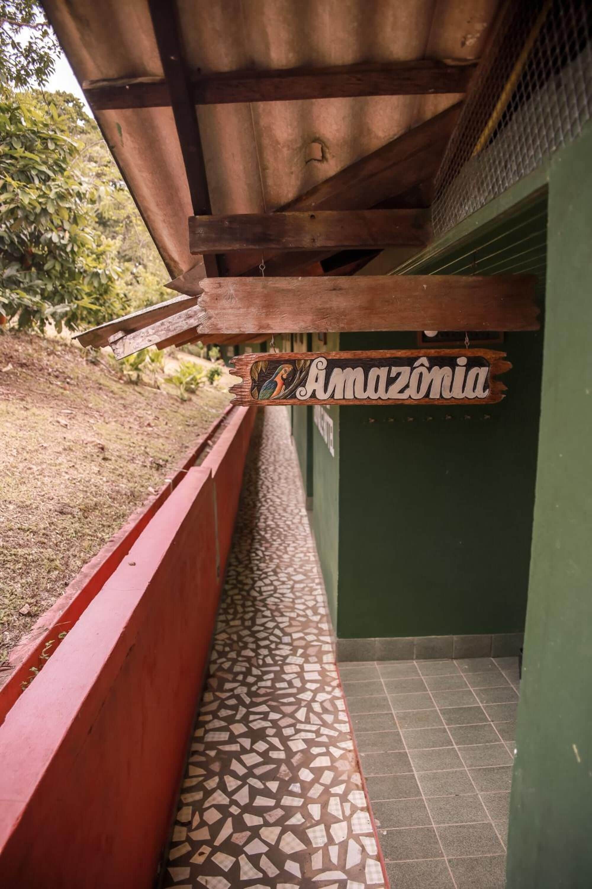 Un pasillo con piso de baldosas, un letrero de madera que dice 'Amazonia' y una pared roja.