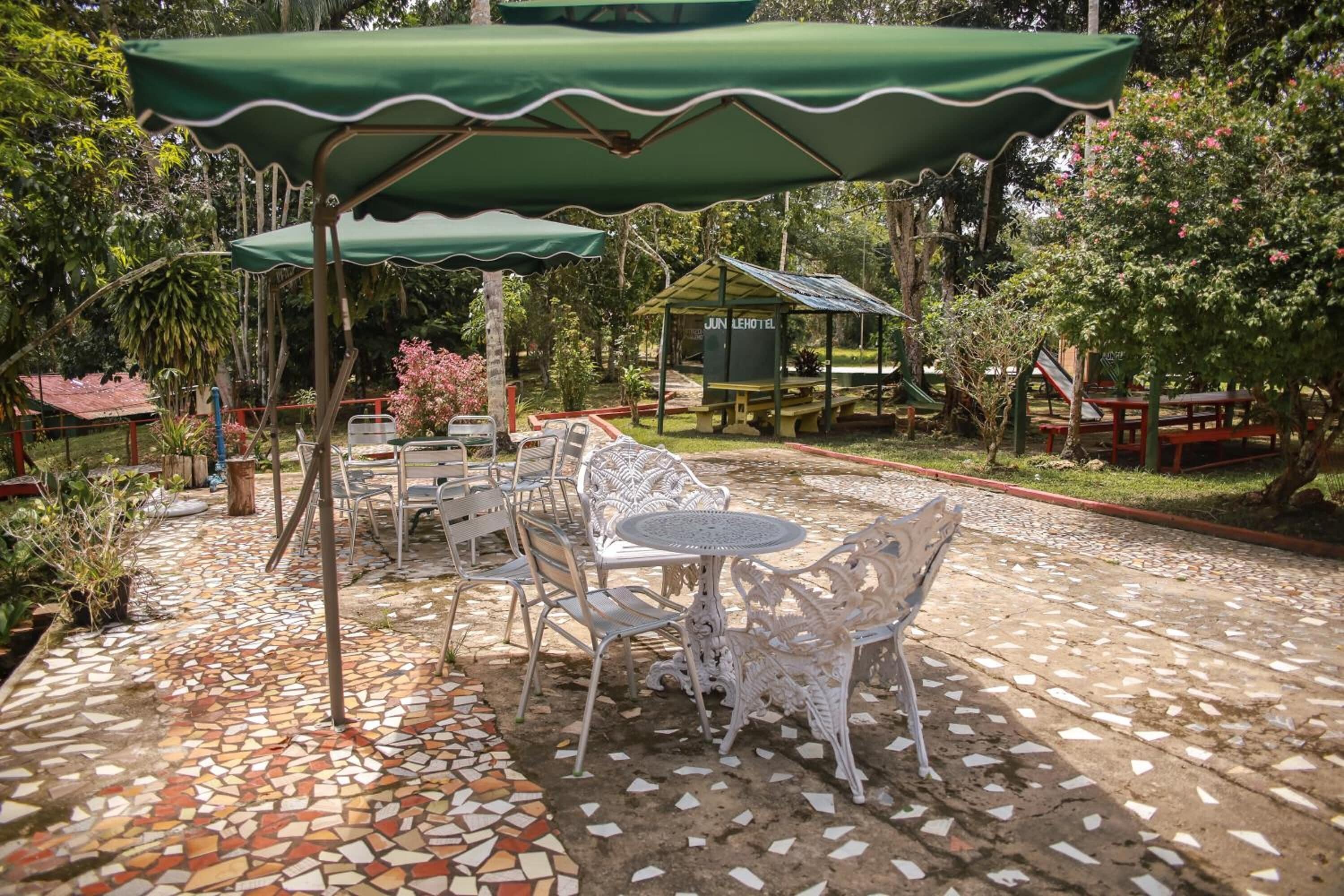 A patio area with outdoor seating, a covered table, and a small building labeled "JUN LEHOTEL".