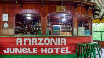 A wooden bar area with a sign reading "AMAZÔNIA JUNGLE HOTEL" and a "BAR" sign above it.