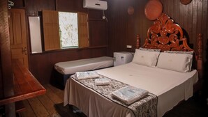 Ein Zimmer aus Holz mit einem Bett, einer Bank, einem kleinen Tisch und einem Fenster mit Vorhängen.