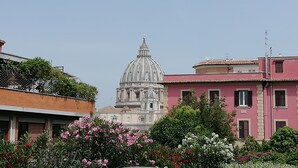 Une vue d’un bâtiment historique surmonté d’un dôme, entouré d’immeubles résidentiels et d’une végétation luxuriante.
