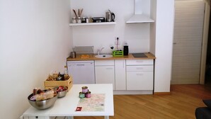 Une cuisine de taille réduite avec des meubles blancs, un lave-vaisselle et un plan de travail sur lequel sont disposés divers objets.