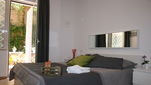Une chambre à coucher avec un lit, une table de chevet, un miroir et une vue sur l’extérieur.