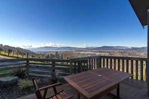 A wooden deck with a table and chairs overlooking a cityscape.