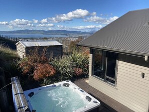A hot tub in a backyard with a view of a body of water and mountains in the distance. - The Lookout - Rotorua Views, Spa Pool, Sleeps 7 (Rotorua Township)