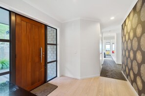 A modern hallway with a wooden door, a glass partition, and a patterned wall. - The Lookout - Rotorua Views, Spa Pool, Sleeps 7 (Rotorua Township)
