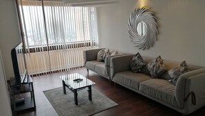 A modern living room with a sofa, coffee table, and decorative mirror. - Polanco Super Lujo (Mexico City)