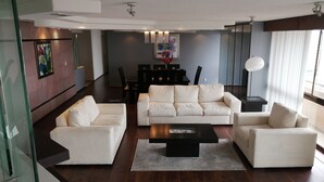 A modern living room with a white sofa set, a coffee table, and a dining area in the background. - Polanco Super Lujo (Mexico City)