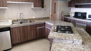 A modern kitchen with granite countertops, stainless steel appliances, and wooden cabinetry. - Polanco Super Lujo (Mexico City)
