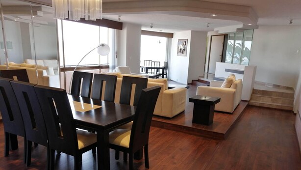 A spacious living area with a wooden dining table and chairs, a sofa, and a coffee table. - Polanco Super Lujo (Mexico City)