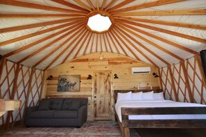 Ein gemütliches Interieur mit Holzbalkendecke, einem Bett, einem Sofa und einer Tür.