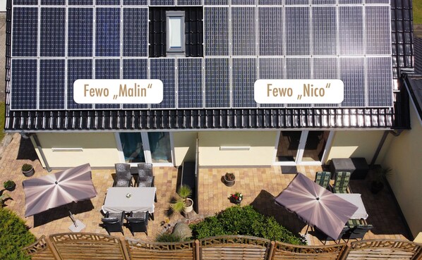 Un toit-terrasse équipé de panneaux solaires, doté d’un espace salon extérieur et agrémenté de plantes en pot.