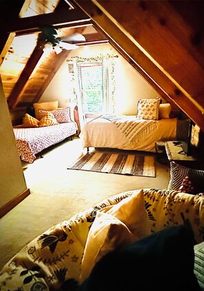 A cozy attic bedroom with a sloped ceiling, a bed, a desk, and a window with a view. - Majestic, private cabin with hot tub/multiple deck...a little taste of heaven! (Dahlonega)