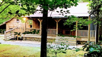 A rustic wooden cabin with a porch and a small staircase leading to a deck.