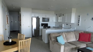 A compact living space with a kitchenette, a dining area with a table and chairs, and a sofa with cushions.