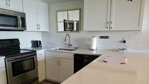 A modern kitchen with white cabinets, a stainless steel stove, a microwave, and a sink.