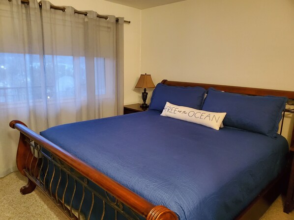 A neatly made bed with blue bedding, a pillow with text, and a wooden headboard. - Oceanfront 4th floor, Balcony with Spectacular Ocean Views (Seaside)