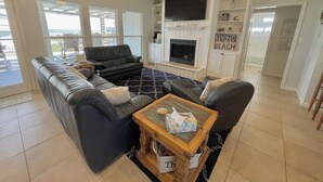 A living room with a large sectional sofa, a wooden coffee table, and a fireplace. - PORTKEY - 2nd Row, Beach view, 4 bedroom, Sleeps 12 (Crystal Beach)