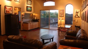 A spacious living area with a sliding glass door leading to a patio, a kitchen with a refrigerator, and a dining area with a table and chairs. - The motorsport studio (Cave Creek)