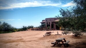 A building with a patio area, a wheelbarrow, and a picnic table. - The motorsport studio (Cave Creek)