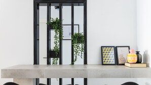 A modern dining area with a long table, black chairs, and a decorative plant. - Special Prices Urban Athens Apartment 2 min walk from metro (Athina)