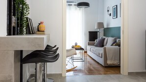 A modern kitchen with a bar area, a dining table, and a sofa in the adjacent living room. - Special Prices Urban Athens Apartment 2 min walk from metro (Athina)