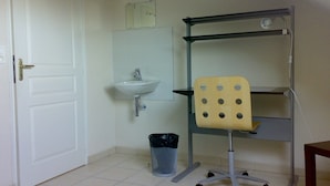 A small, clean room with a white door, a sink, a chair, and a trash bin. - New apartment for rent with luxurious furnishings (Saint-Nazaire)