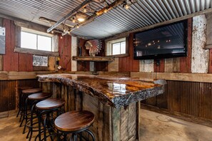 A rustic bar area with a wooden bar counter, bar stools, and a television mounted on the wall. - Maple Station - Raystown Lake: Seven Points Marina (Hesston)