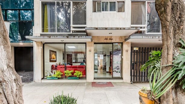 A two-story building with a ground-level entrance featuring a red sofa and glass doors. - Capital O Hotel Suites Marne, Mexico City (Mexico City)