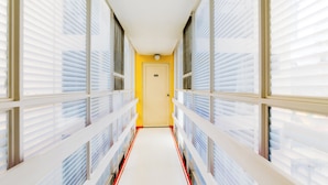 A corridor with white railings and a yellow door at the end. - Capital O Hotel Suites Marne, Mexico City (Mexico City)