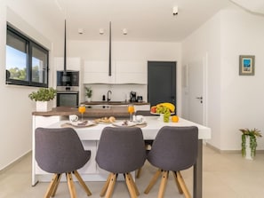 A modern kitchen with a central island, three grey chairs, and a dining table. - Villa Meri 2 by Interhome (Trogir/Okrug Gornji)