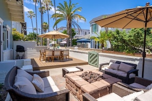Un espace patio aménagé avec du mobilier d’extérieur, un barbecue et des parasols.